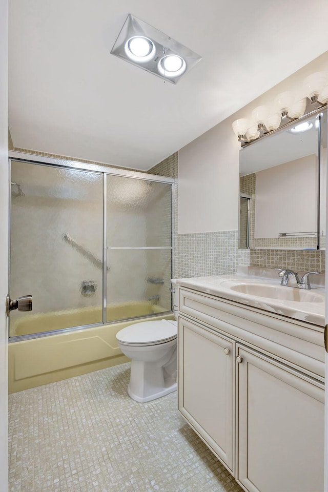 bathroom featuring enclosed tub / shower combo, tile patterned flooring, toilet, vanity, and tile walls