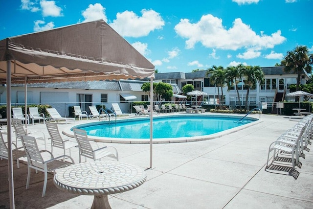 community pool with fence and a patio