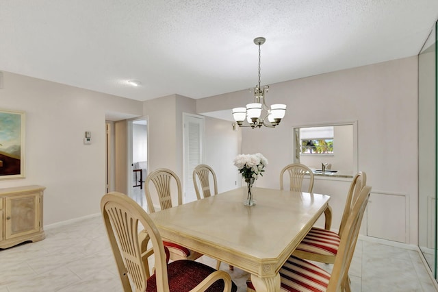 dining space with a notable chandelier, baseboards, and a textured ceiling