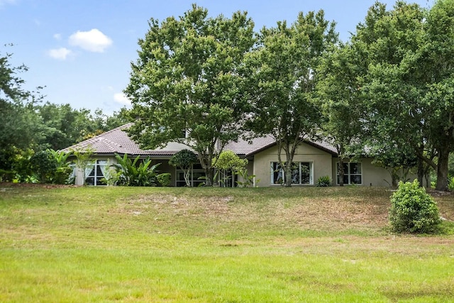 view of front of property with stucco siding, a tile roof, and a front lawn