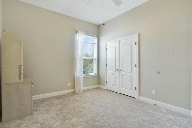 unfurnished bedroom featuring carpet, baseboards, a closet, and ceiling fan