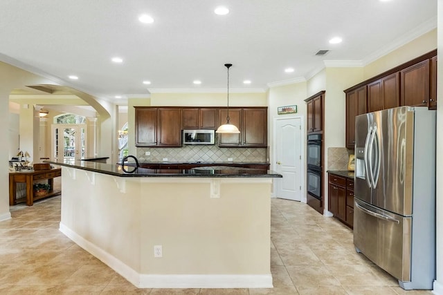 kitchen featuring visible vents, arched walkways, decorative backsplash, appliances with stainless steel finishes, and dark countertops