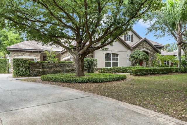 view of front of house featuring stone siding, stucco siding, and a tile roof