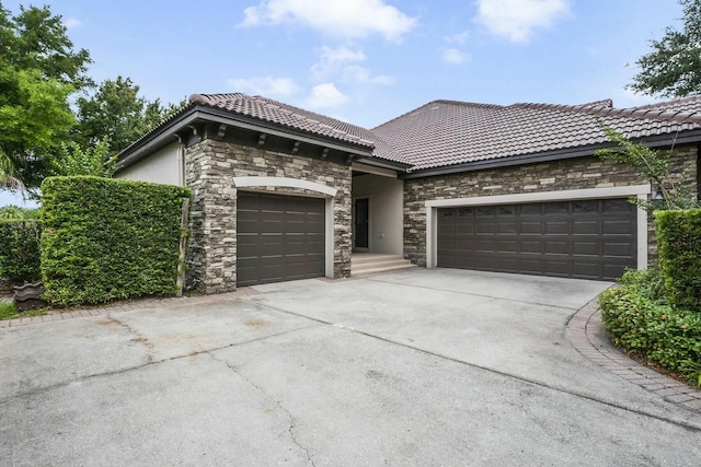 view of front of property with a garage, stone siding, concrete driveway, and a tile roof