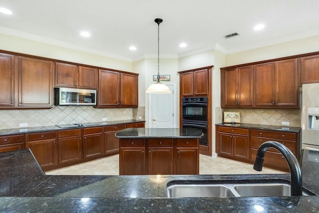 kitchen featuring visible vents, black appliances, a sink, dark stone countertops, and hanging light fixtures