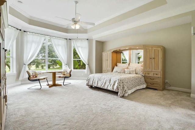 bedroom featuring a raised ceiling, ornamental molding, baseboards, and light carpet