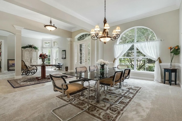 dining space with carpet, ornamental molding, decorative columns, an inviting chandelier, and arched walkways