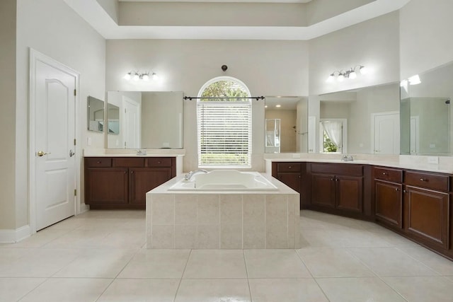 bathroom featuring tile patterned floors, a high ceiling, a garden tub, and a sink