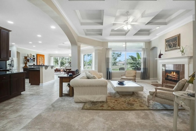 interior space featuring a tiled fireplace, coffered ceiling, recessed lighting, arched walkways, and crown molding