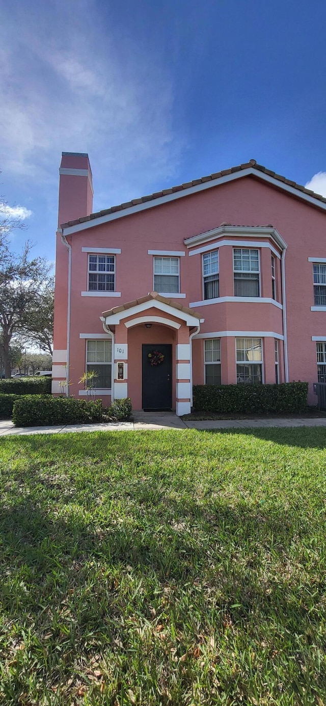 view of front facade with a chimney and a front lawn