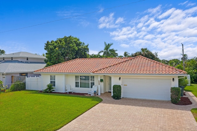 view of front facade with an attached garage, a tiled roof, a front yard, and stucco siding