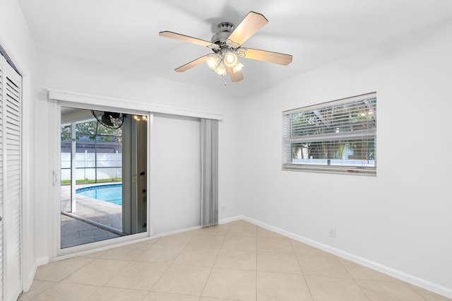 unfurnished room featuring a wealth of natural light, ceiling fan, baseboards, and light tile patterned floors