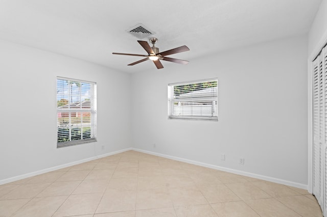 spare room featuring light tile patterned floors, baseboards, visible vents, and a ceiling fan