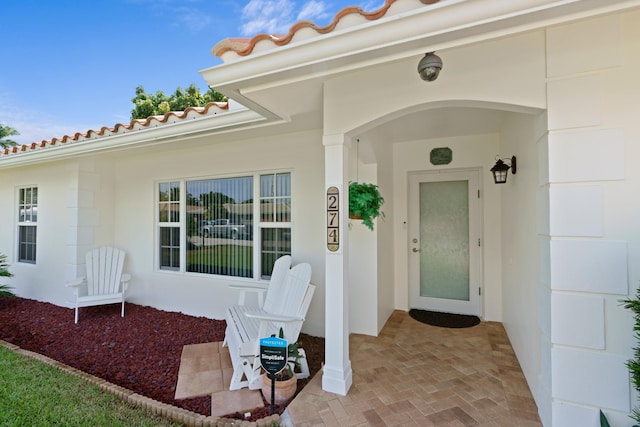 view of exterior entry with a tile roof and stucco siding