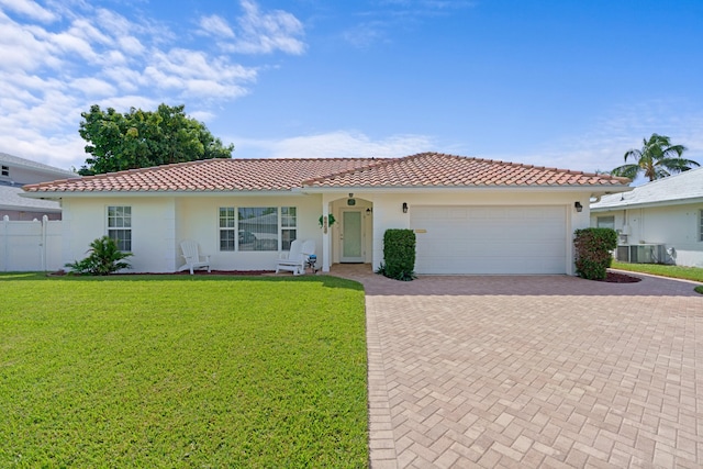 ranch-style house featuring an attached garage, a tile roof, decorative driveway, stucco siding, and a front yard