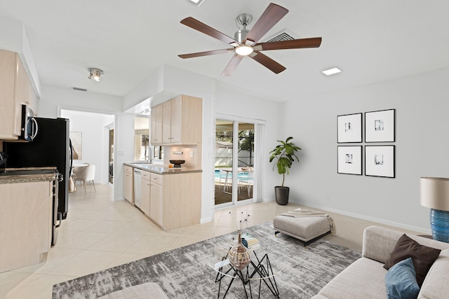 living area featuring light tile patterned floors, ceiling fan, visible vents, and baseboards