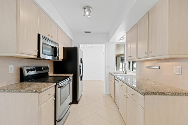 kitchen with stainless steel appliances, light brown cabinets, a sink, and visible vents