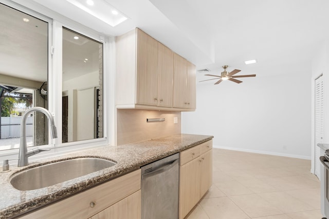 kitchen with a sink, stone countertops, stainless steel dishwasher, and light brown cabinetry