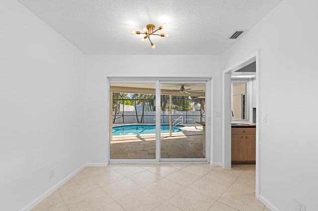 doorway featuring visible vents, a textured ceiling, baseboards, and light tile patterned flooring