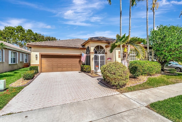 view of front of property featuring decorative driveway, an attached garage, a tile roof, and stucco siding