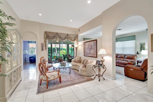 living area with arched walkways, light tile patterned floors, recessed lighting, visible vents, and baseboards