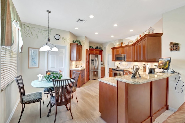 kitchen featuring stainless steel appliances, backsplash, visible vents, and a peninsula