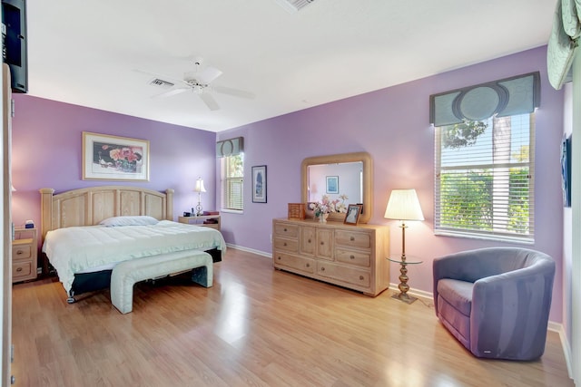 bedroom with ceiling fan, light wood finished floors, visible vents, and baseboards