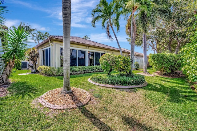 exterior space featuring central AC, a front lawn, a tile roof, and fence