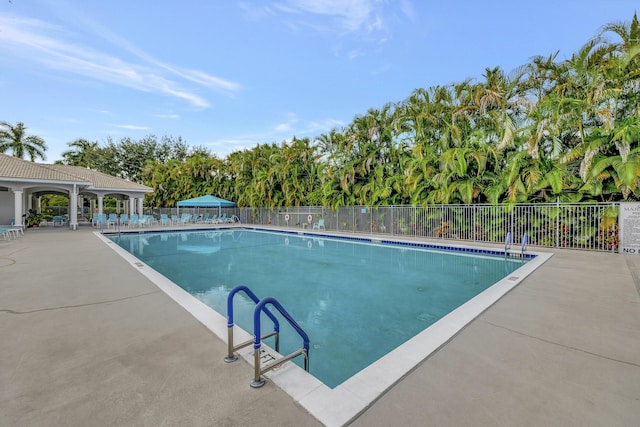 community pool with a patio area and fence