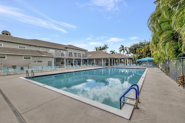 community pool with a patio area and fence