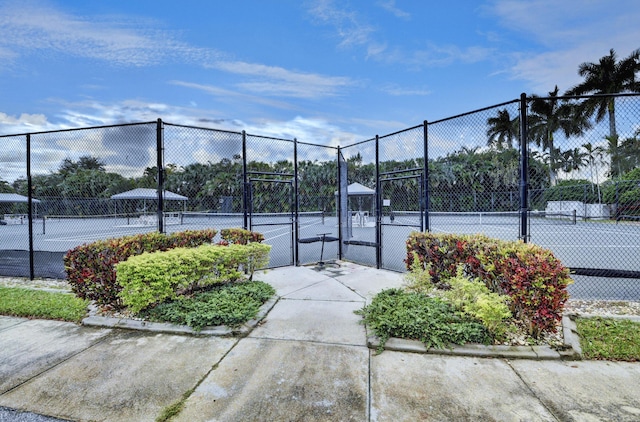 view of tennis court featuring a gate and fence