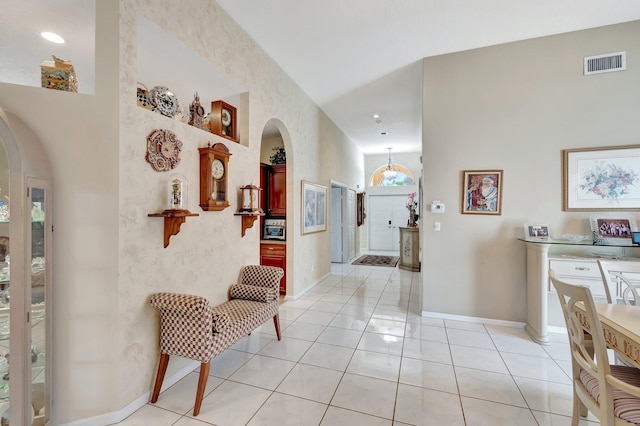 hallway featuring arched walkways, visible vents, baseboards, and light tile patterned floors