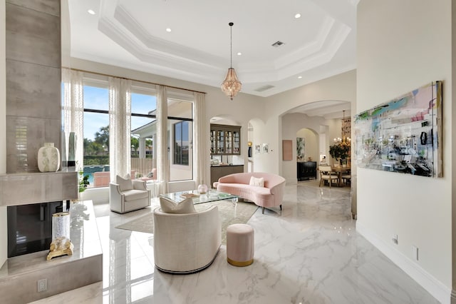 living area with arched walkways, visible vents, marble finish floor, a tray ceiling, and crown molding