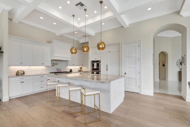 kitchen featuring light wood-type flooring, visible vents, white cabinets, and backsplash