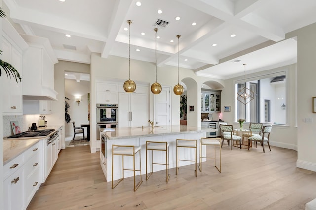 kitchen with light wood finished floors, tasteful backsplash, visible vents, stainless steel double oven, and white cabinetry