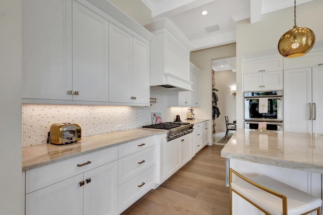 kitchen with light stone counters, tasteful backsplash, appliances with stainless steel finishes, light wood-style floors, and white cabinetry