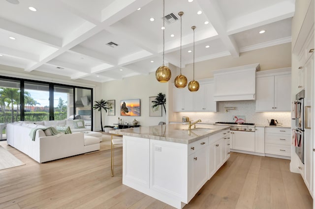 kitchen featuring open floor plan, light wood finished floors, custom exhaust hood, and visible vents