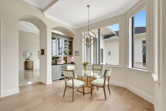 dining room with crown molding, an inviting chandelier, light wood-style floors, beverage cooler, and baseboards