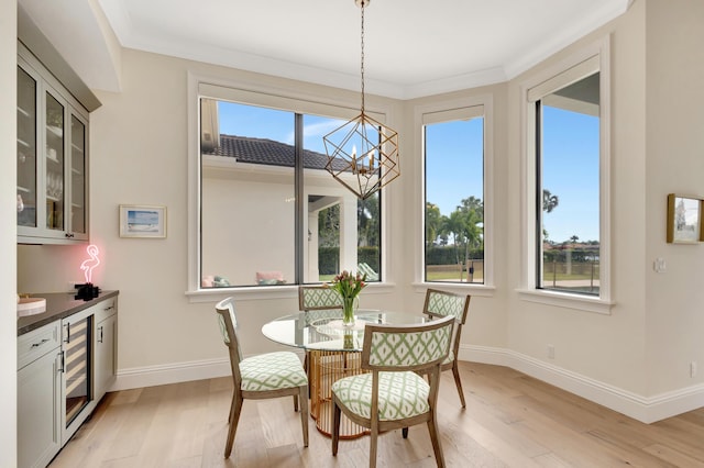 dining area with beverage cooler, light wood finished floors, an inviting chandelier, and baseboards