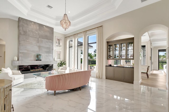 living room with arched walkways, marble finish floor, a raised ceiling, visible vents, and a large fireplace