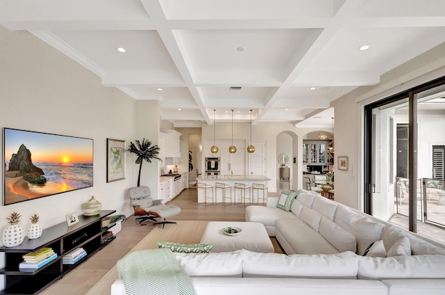 living room with light wood-type flooring, beam ceiling, coffered ceiling, and arched walkways