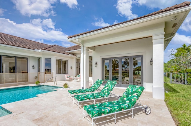 rear view of house featuring a tiled roof, fence, a patio, and french doors