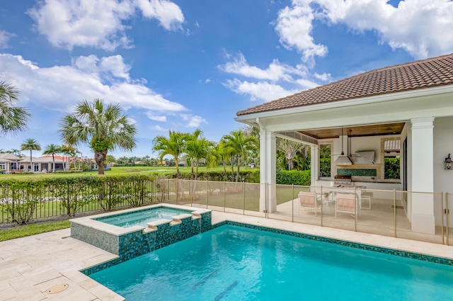 view of pool featuring a patio area, a fenced backyard, a pool with connected hot tub, and exterior kitchen