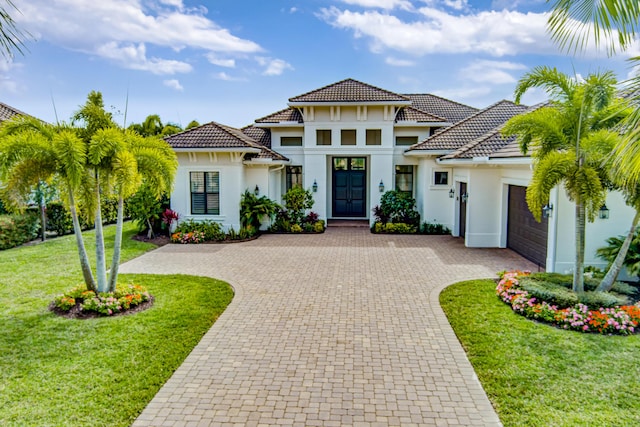 view of front of home featuring a garage, decorative driveway, a front lawn, and stucco siding