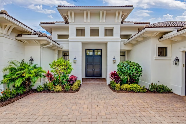 entrance to property featuring a tiled roof and stucco siding