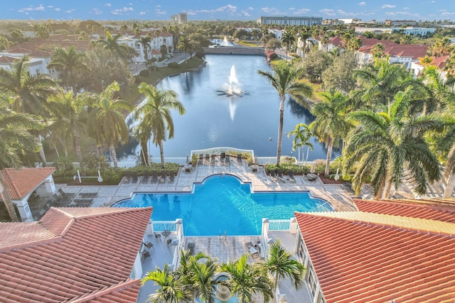 community pool featuring a patio area, a water view, and fence