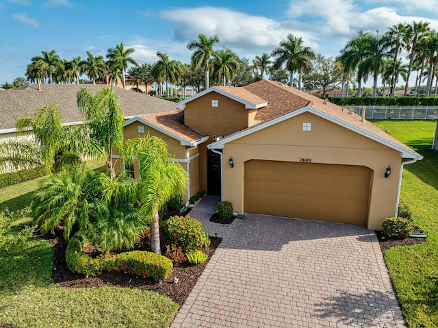 view of front of home with a garage, decorative driveway, fence, and stucco siding