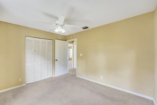 unfurnished bedroom featuring a closet, visible vents, light carpet, ceiling fan, and baseboards