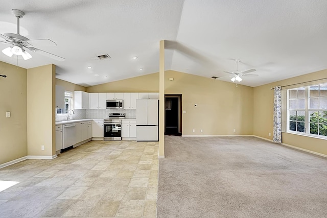 kitchen featuring stainless steel appliances, light countertops, open floor plan, a healthy amount of sunlight, and white cabinets