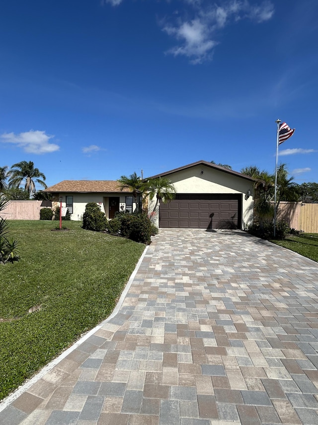 ranch-style house featuring an attached garage, fence, a front lawn, and stucco siding